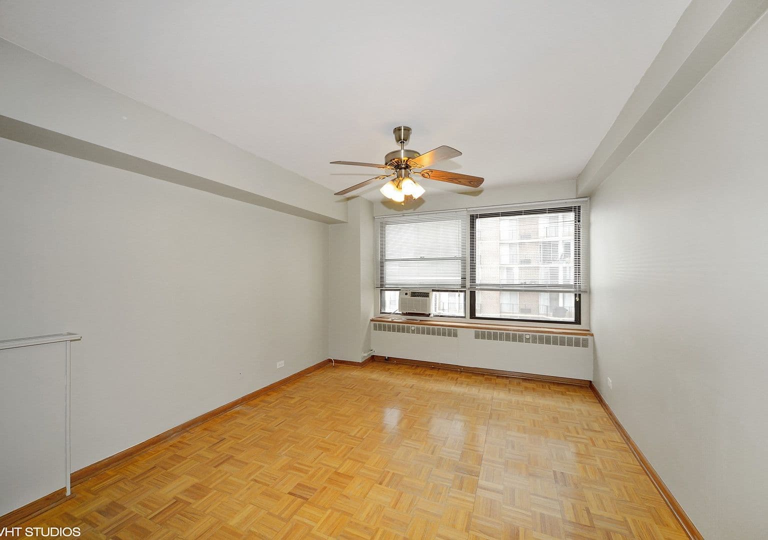 Bright bedroom offers parquet floors and a ceiling fan.