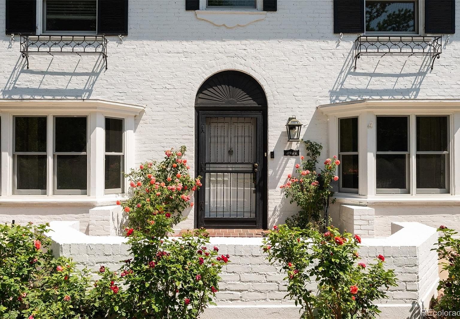 Arched black front door flanked by climbing roses