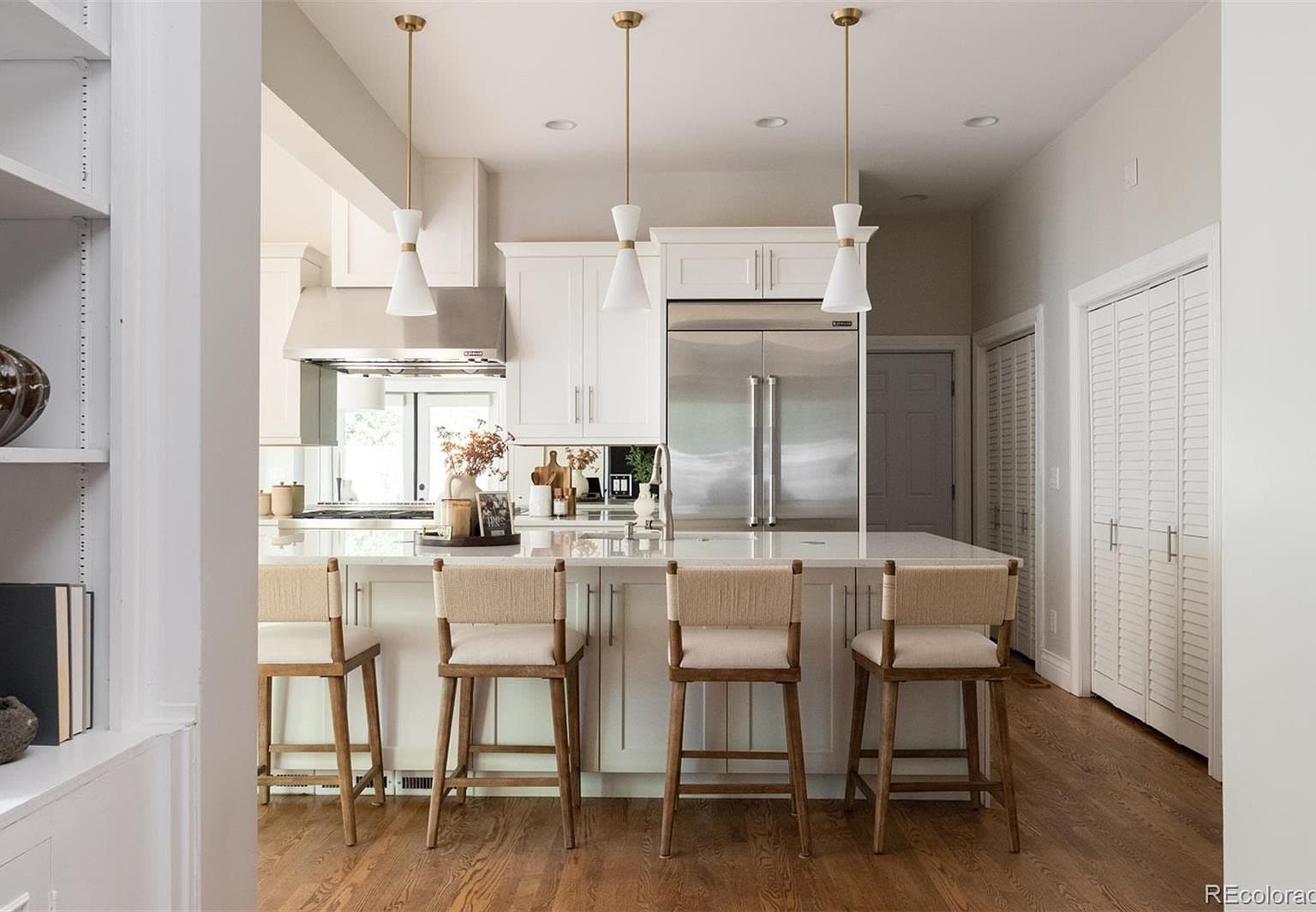 White chef's kitchen with brass pendants and bar seating
