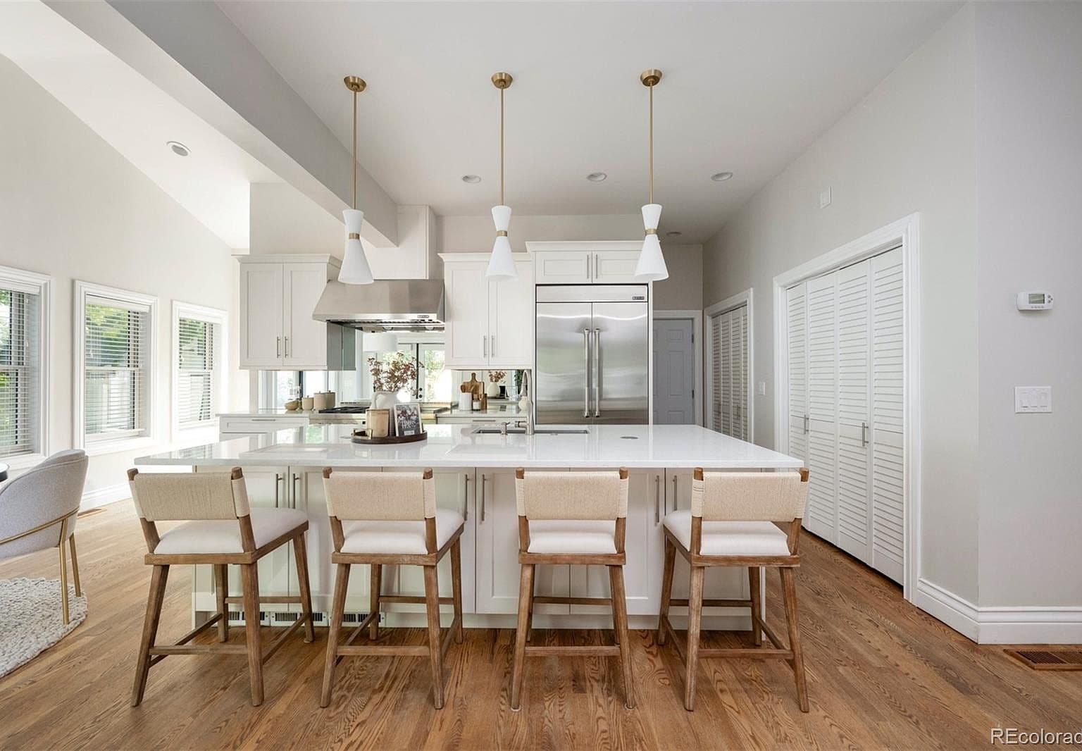 Four-seat quartz island beneath sculptural white pendants