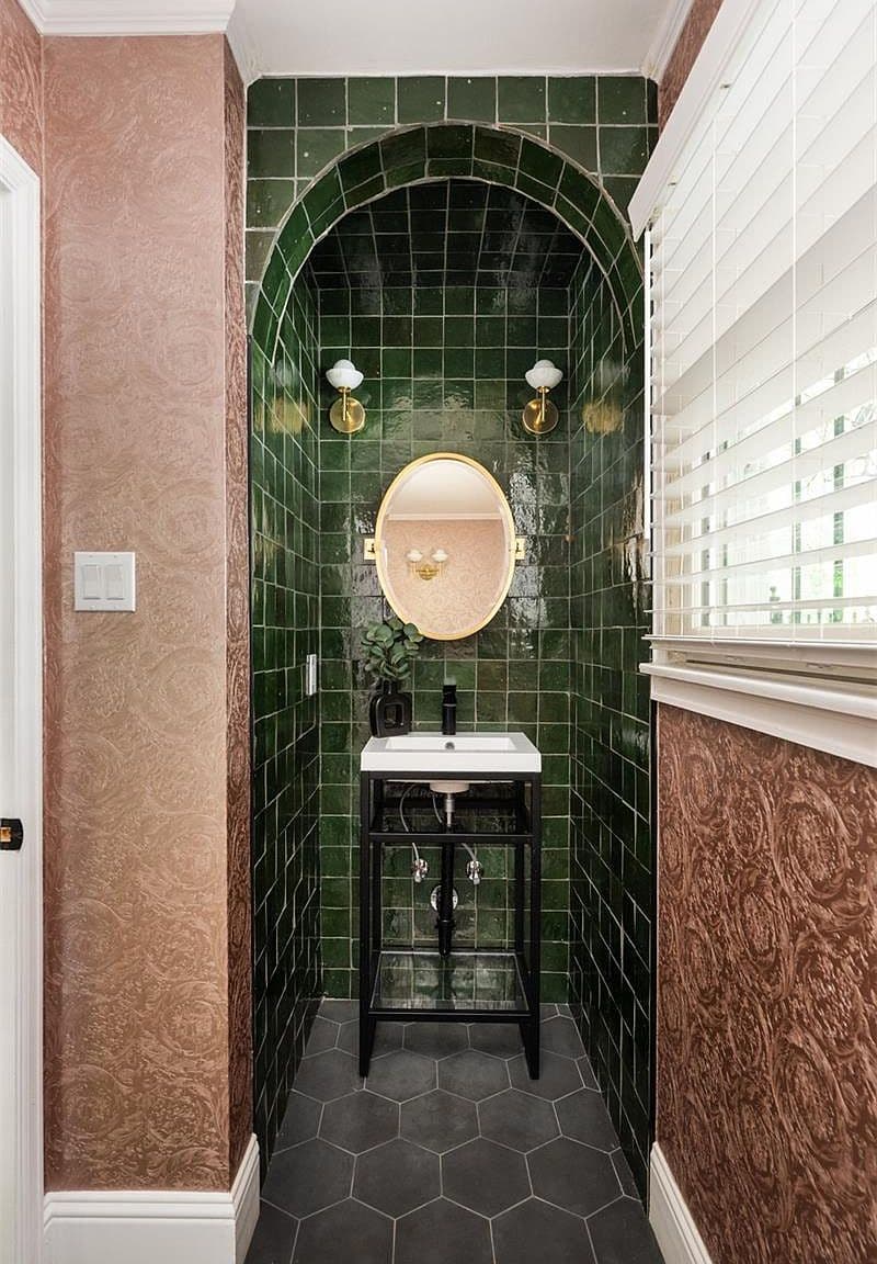 Emerald-tiled powder bath with arched niche and brass accents