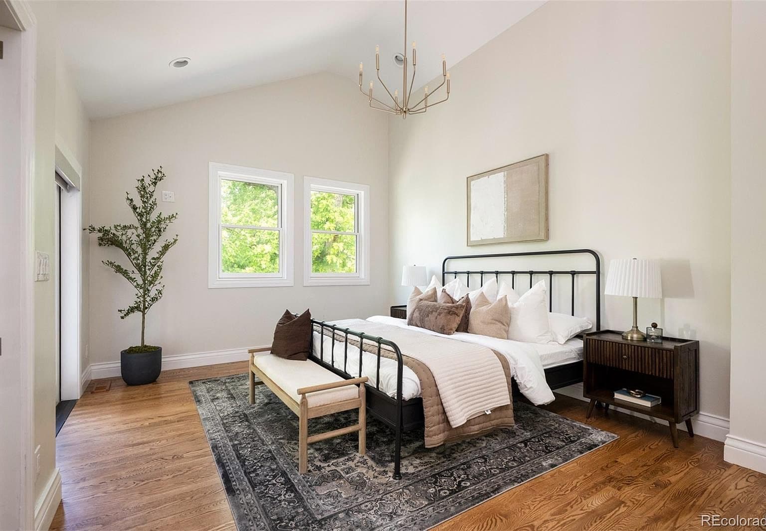 Vaulted primary suite with brass chandelier