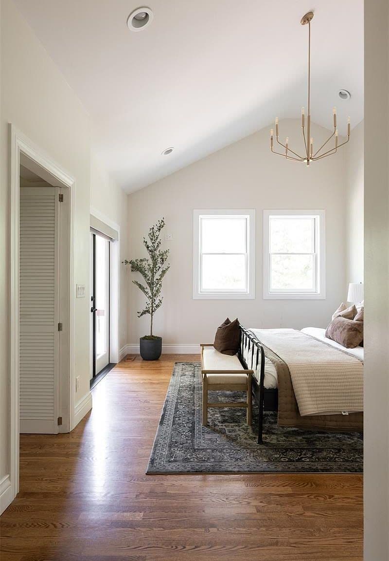 Airy primary bedroom with olive tree and chandelier