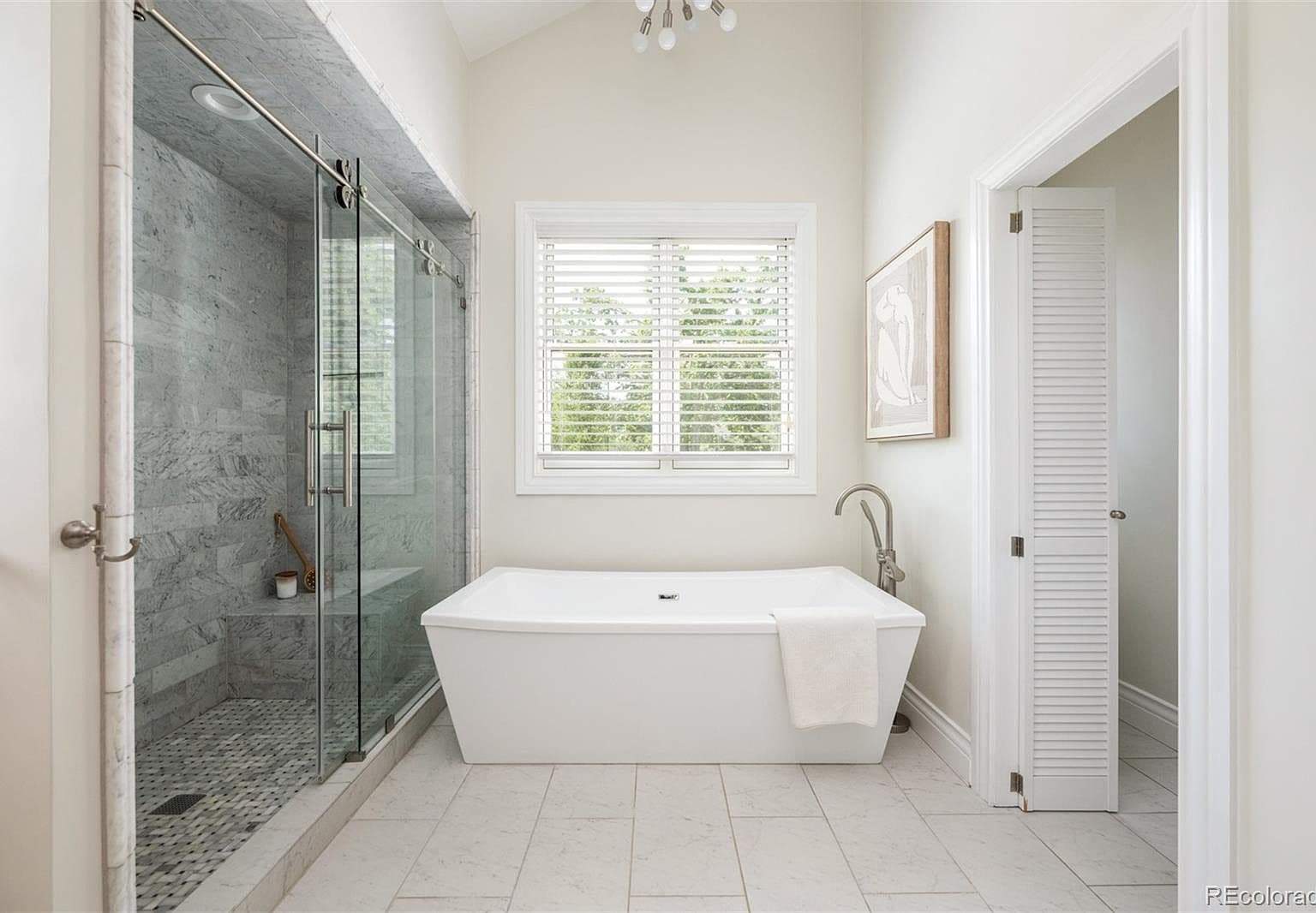 Freestanding tub beside marble walk-in shower