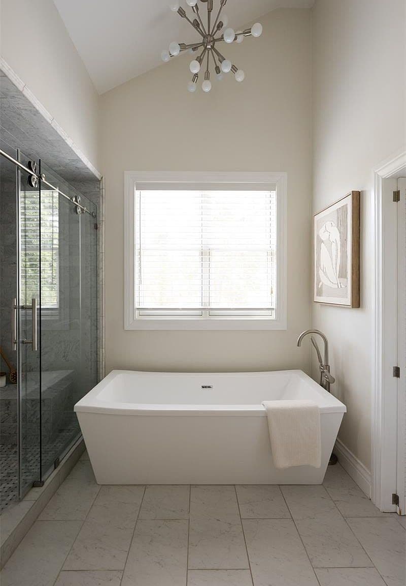 Soaking tub beneath window with sputnik chandelier