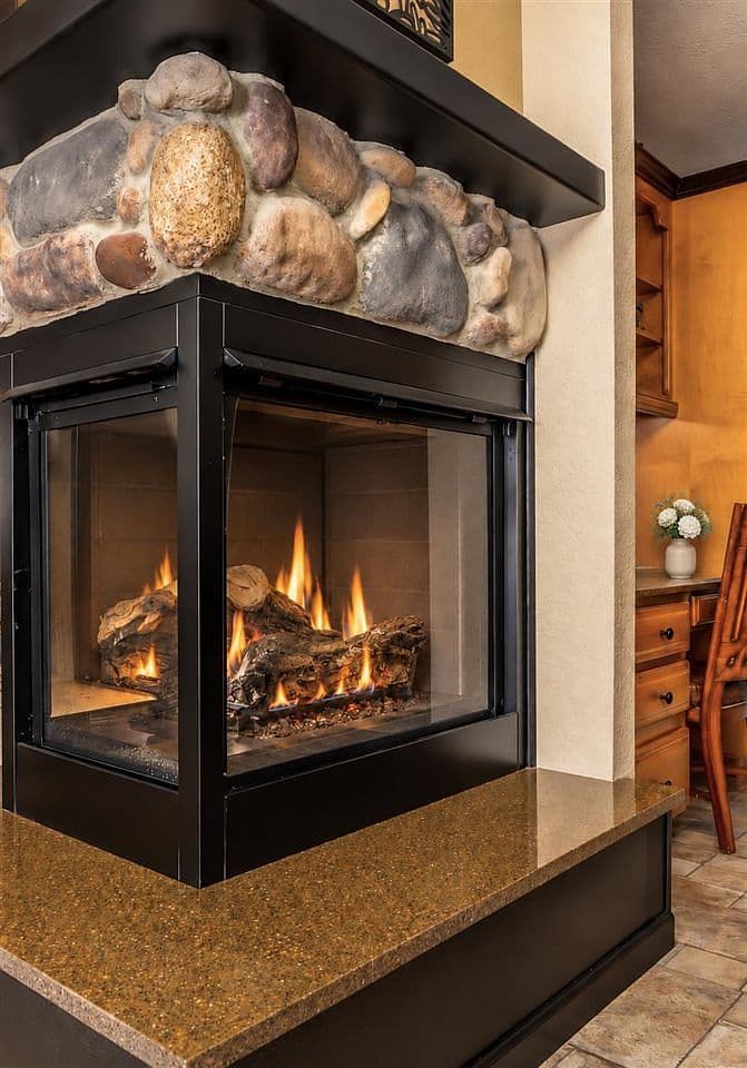 Three-sided river-rock fireplace delivers cozy, upscale warmth.